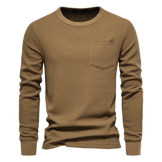 A women's long sleeve waffle-knit tee with a relaxed fit and chest pocket. The 80% cotton/20% polyester blend offers softness and breathability, with textured fabric that provides lightweight warmth. Designed for easy everyday wear in spring and fall seasons.