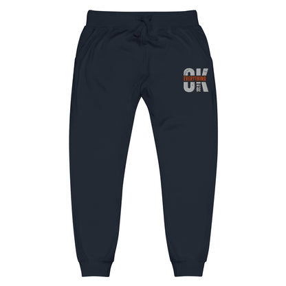 Navy blue unisex fleece sweatpants with ribbed waistband, cuffed ankles, and front cross pockets. Shown flat to highlight the 5-thread stitching and soft fleece lining.