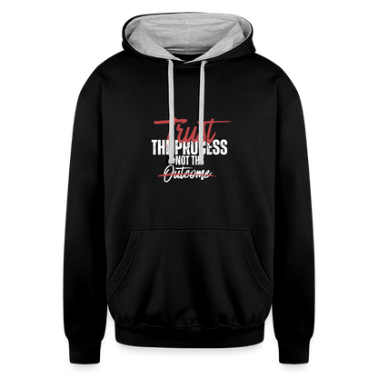 A unisex black/gray contrast hoodie featuring a double-layered hood with a bold contrasting inner fabric and matching flat lace drawcords. The front displays a motivational print reading "Trust the Process Not the Outcome" in a clean, modern font. Made from a soft 80% cotton/20% polyester blend (8.3 oz midweight fabric), it has ribbed cuffs and hem for a snug fit. Designed for tag-free comfort with a tear-out label, this stylish pullover by ADON LUXE is perfect for everyday wear. 